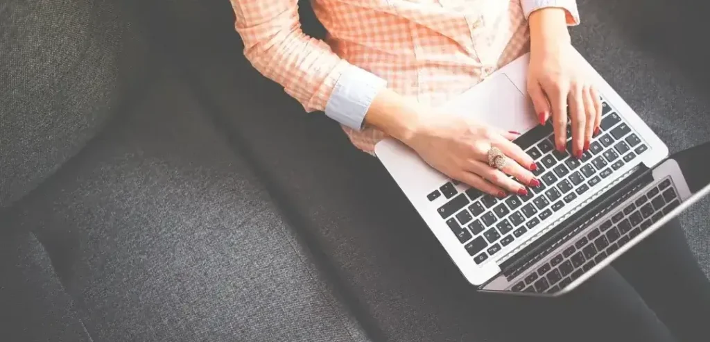 blogindlæg med salgsfokus - kvinde sidder med laptop i sit skød og skriver